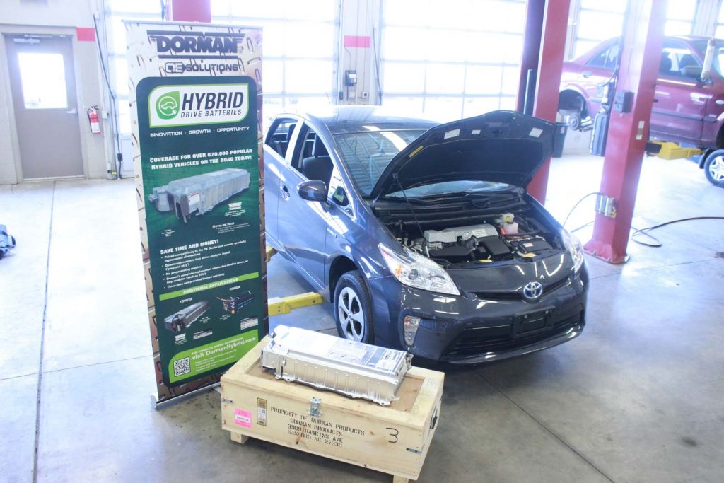 A hybrid vehicle next to a hybrid battery display sign