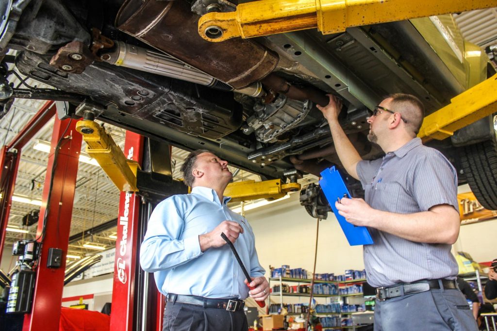 technician inspecting under a car in the shop