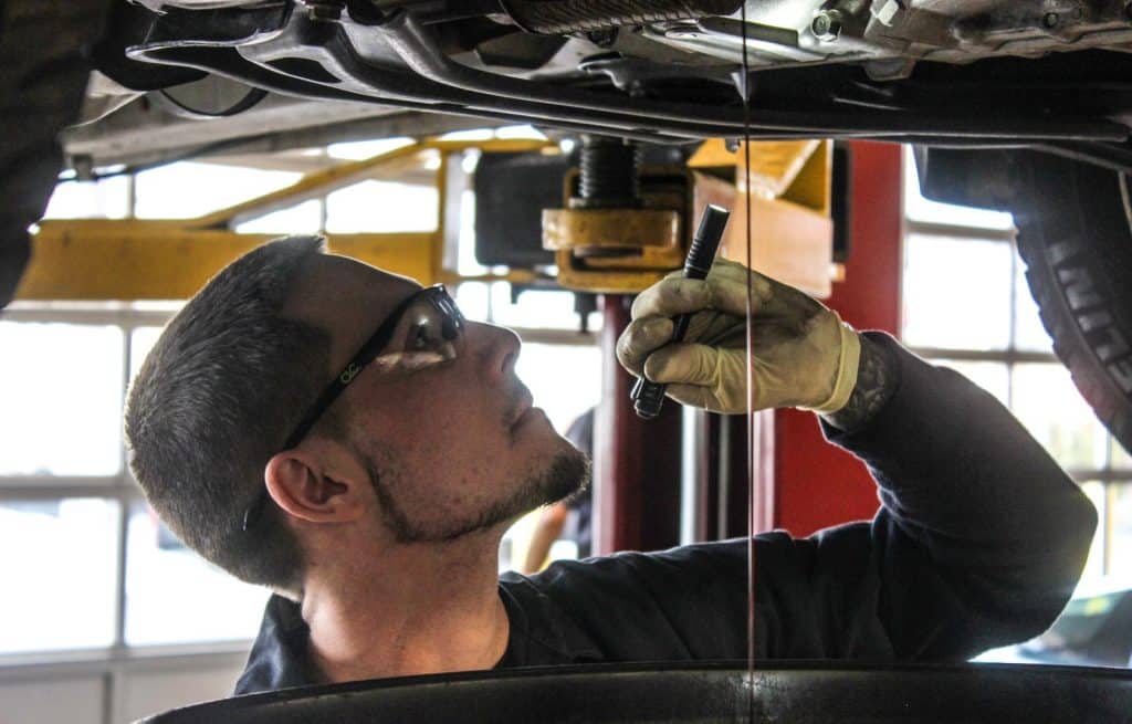 mechanic inspecting underside of vehicle