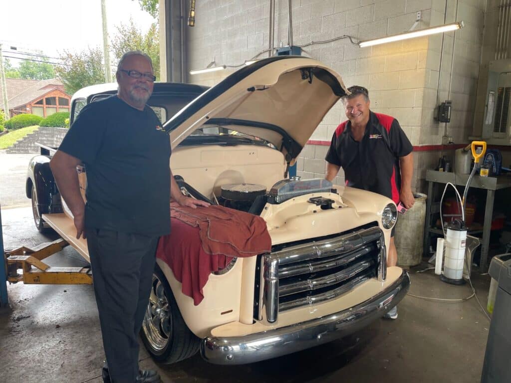 men standing by open car hood