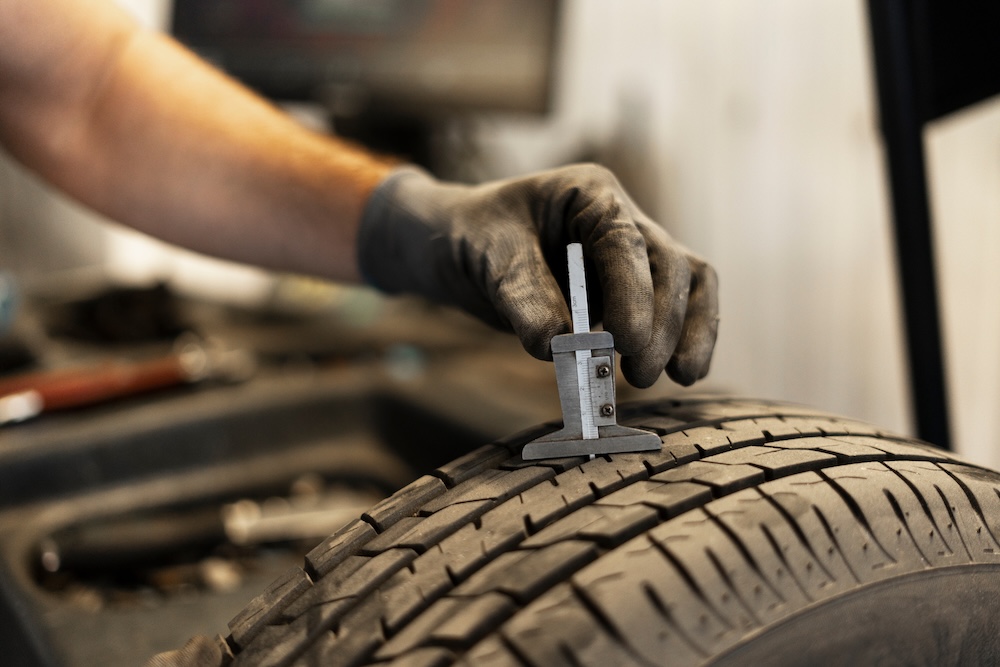 Mechanic measuring tire tread depth using caliper